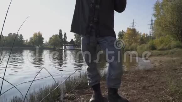 留着长胡子的渔夫用钓竿在河岸上站着那个人望着远处遮住了眼睛视频的预览图