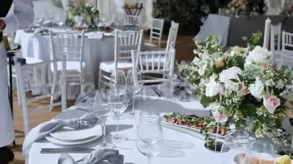 提供各种美味菜肴的大桌子和白色桌布的宴会玫瑰花布置视频的预览图