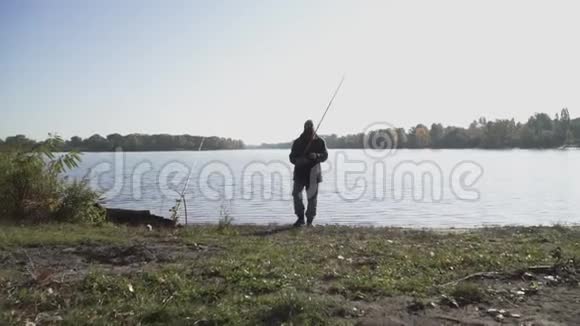 有胡子的渔夫拿着鱼竿从相机旁经过这个人从事一种爱好河流捕鱼慢动作视频的预览图
