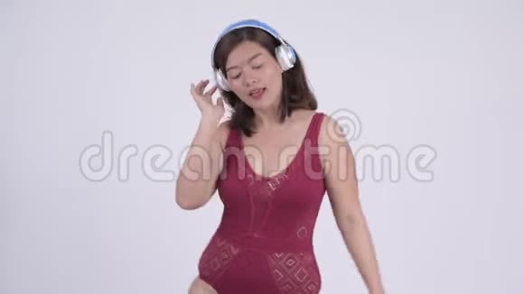 年轻快乐的亚洲旅游妇女跳舞和听音乐视频的预览图