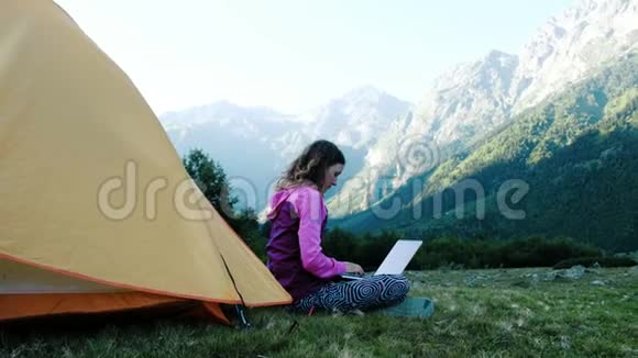 旅游妇女使用笔记本电脑的本质自由职业者打字在帐篷附近的背景下旅行视频的预览图