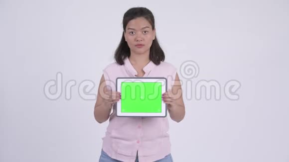 年轻快乐的亚洲女商人展示数码平板电脑看上去很惊讶视频的预览图