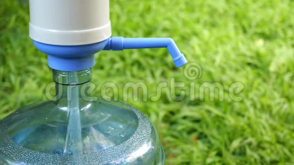人的手把一个透明的水壶装满冷水从一个大瓶子或冷却器里用水泵反对视频的预览图