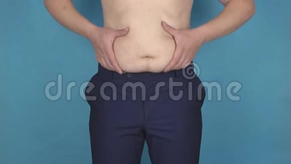一个年轻人在厚厚的反脂肪胃上摩擦他的脂肪皱褶这是一种错误的生活方式和营养的概念视频的预览图