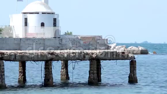 在希腊塞萨洛尼基地区的海边和一个旧水泥码头后面的希腊东正教小教堂视频的预览图