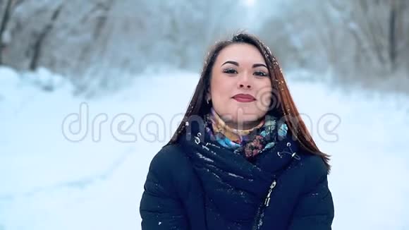 特写一个美丽的年轻女孩在寒冷的白雪覆盖的森林里享受冬天的散步视频的预览图