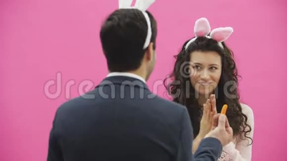 美丽的年轻女孩站在粉红色的背景上在这期间头上有兔子的耳朵一个人站着视频的预览图