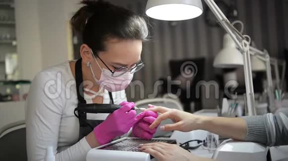 一只带指甲的美甲手躺在一个穿着粉红色卫生手套的美甲师的手上大师经典法语视频的预览图