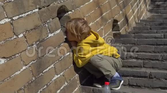 穿着黄色夹克的小男孩穿过中国长城的洞口视频的预览图