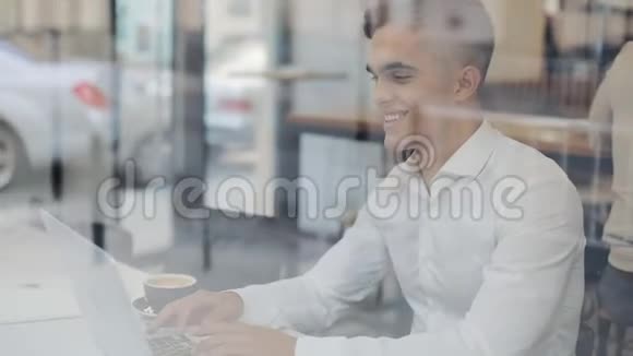 年轻快乐的商人在咖啡馆里用笔记本电脑工作他在读好消息成功人士日常生活视频的预览图