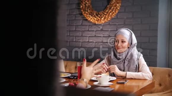 坐在咖啡馆里谈笑风生的年轻穆斯林妇女视频的预览图