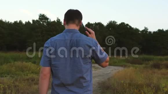 人在森林路上旅行在智能手机上交谈森林里的游客1男人走路时打电话视频的预览图