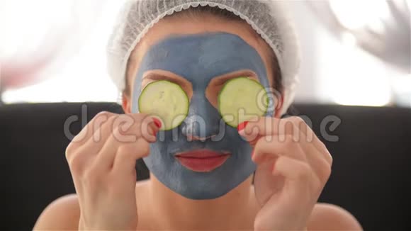 一个女孩脸上戴着面具头上戴着毛巾用黄瓜和微笑闭上眼睛妇女视频的预览图