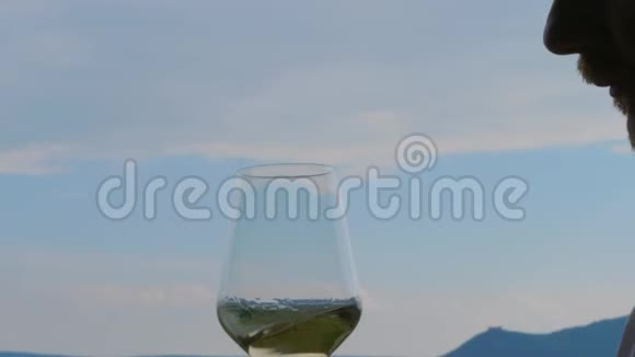 人在蓝天上旋转嗅嗅品白葡萄酒视频的预览图