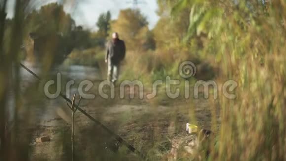 蓄胡子的人朝相机走去看着水面杆固定在河岸上的专用棒中视频的预览图