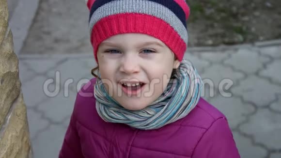 一个美丽的白人小女孩戴着条纹帽子蓝眼睛看着摄像机视频的预览图