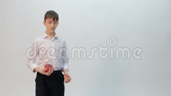 一个戴着眼镜穿着白色衬衫的少年扑上来抓住了一个红苹果白色背景复印空间视频的预览图