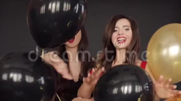 漂亮的双胞胎穿着红色和黑色的连衣裙玩着气球喷着纸屑视频的预览图