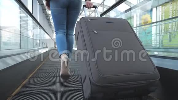 女商人带着行李穿过候机厅的腿穿着高跟鞋在自动扶梯上行走的少女视频的预览图
