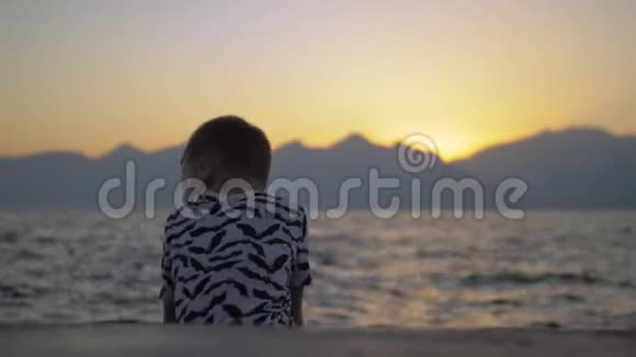 日落时海滩上孤独的孩子视频的预览图