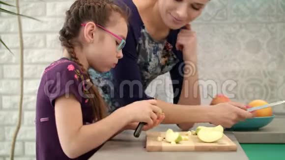 女孩和妈妈在厨房吃苹果女孩用刀切苹果视频的预览图