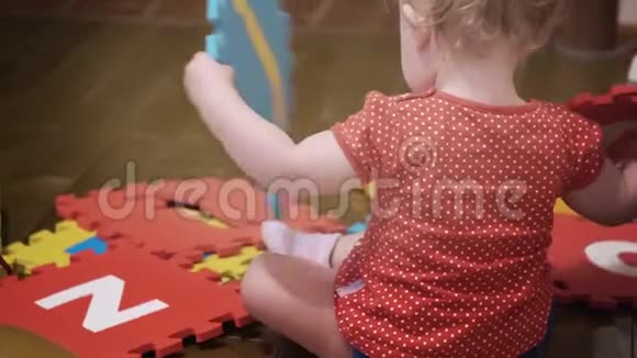 小女孩在家玩彩色拼图地毯瓷砖和字母视频的预览图