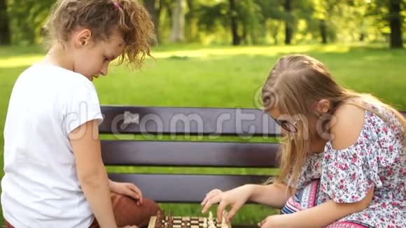 两个学童在公园里的长凳上下棋暑假智力游戏视频的预览图