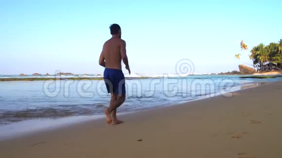 光脚运动员沿着潮湿的沙滩慢跑视频的预览图