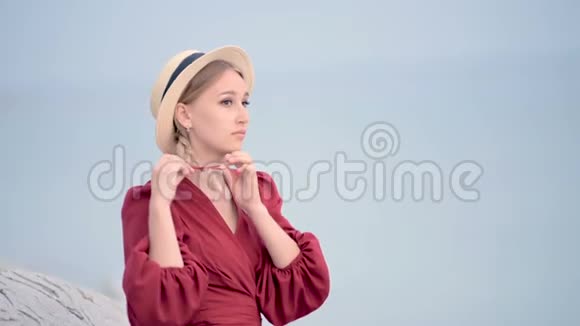 一位穿着红色连衣裙戴着一顶辫子草帽的白种人年轻女子坐在上面她的肖像很吸引人视频的预览图