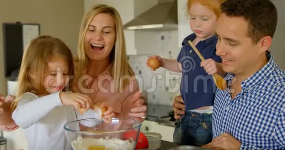 父母教他们的女儿在烤鸡蛋的同时打碎鸡蛋视频的预览图