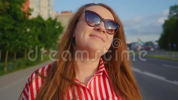 夏天穿红色衣服的年轻女孩的肖像幸福的年轻女子对着镜头微笑抚摸着她的大肚子视频的预览图