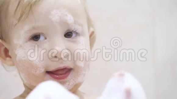 一个可爱的小婴儿在浴室里玩泡沫的肖像视频的预览图