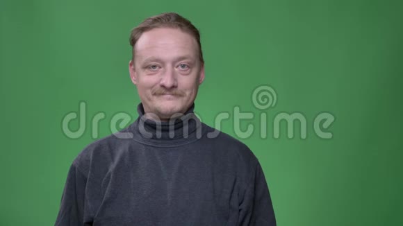 一幅金发中年男子留着胡子在绿色背景下高兴地看着镜头的肖像视频的预览图