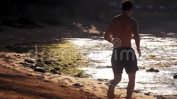 运动员的侧影沿着沙滩向后看视频的预览图