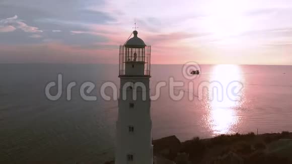 无人机拍摄灯塔海滩灯塔日落在美丽的日落背景下的灯塔视频的预览图