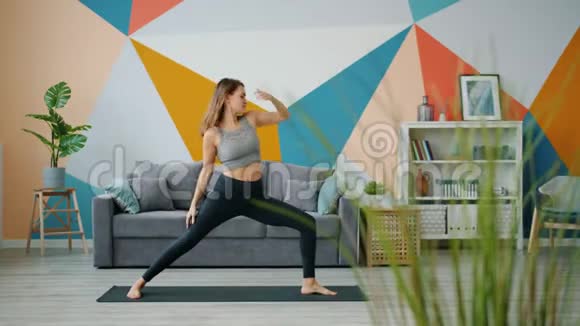 漂亮的女孩在家做瑜伽练习在家在地板上伸展身体视频的预览图