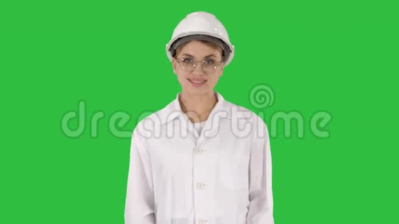 职业女性穿着实验室外套白色硬帽行走在绿色屏幕上微笑Chroma键视频的预览图