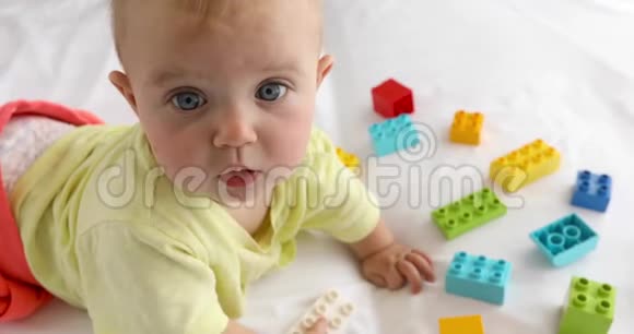 小婴儿躺在玩具之间的白色亚麻布上视频的预览图