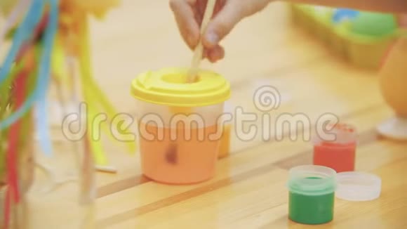 有创意的女孩在罐子里混合和搅拌水女孩选择了绿色来画画复活节的概念桌子上装饰着视频的预览图