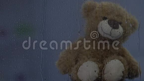 棕色泰迪熊坐在雨窗后灯光闪烁童年视频的预览图