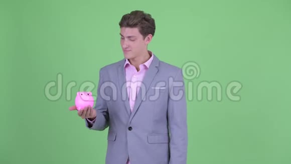 快乐的年轻商人拿着储蓄罐竖起大拇指视频的预览图