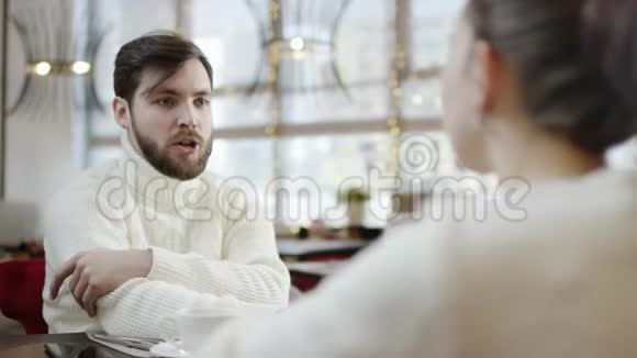 一位成年男子正和一位在餐馆里餐桌旁牵着她手的女人谈话视频的预览图