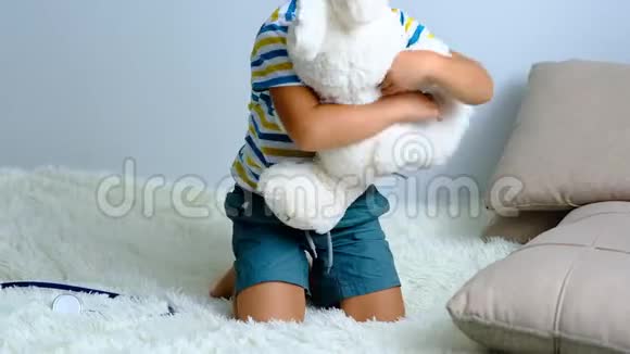 慢动作小男孩在家玩软玩具表现力强的小男孩拥抱她的毛绒朋友的肖像室内视频的预览图