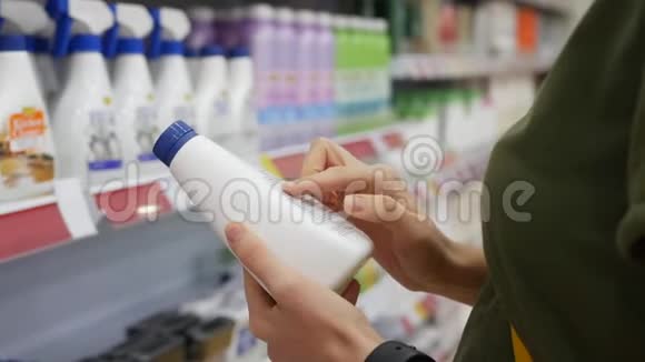 年轻女子在超市里选择家用化学品她读标签的结构特写镜头4k视频的预览图