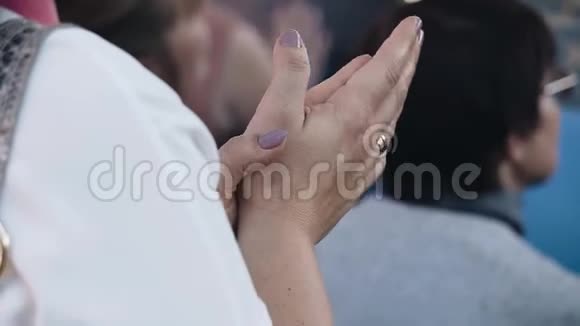 一个戴着戒指的女人向台上的演讲者鼓掌视频的预览图