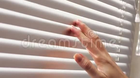 女性用手指将百叶窗的板条分开以看穿视频的预览图