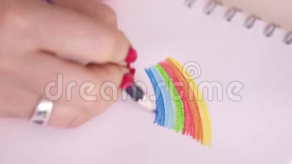 女人在笔记本上画彩虹彩色铅笔红色指甲视频的预览图