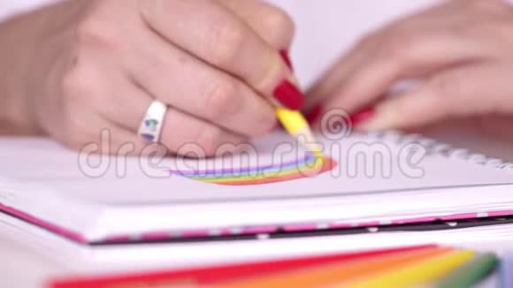 女人在笔记本上画彩虹彩色铅笔红色指甲视频的预览图