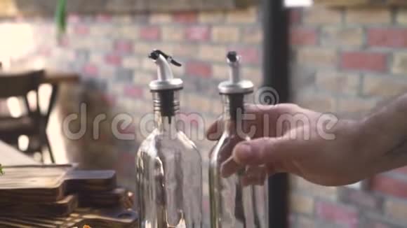 厨师从瓶子里倒橄榄油然后在砖块背景下做沙拉男性手拿橄榄油视频的预览图