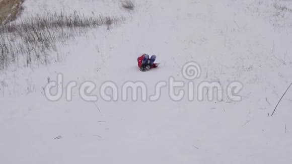 女孩在雪碟上从高高的雪山上翻滚笑了起来圣诞节在寒冷的日子里举行雪的运动会视频的预览图